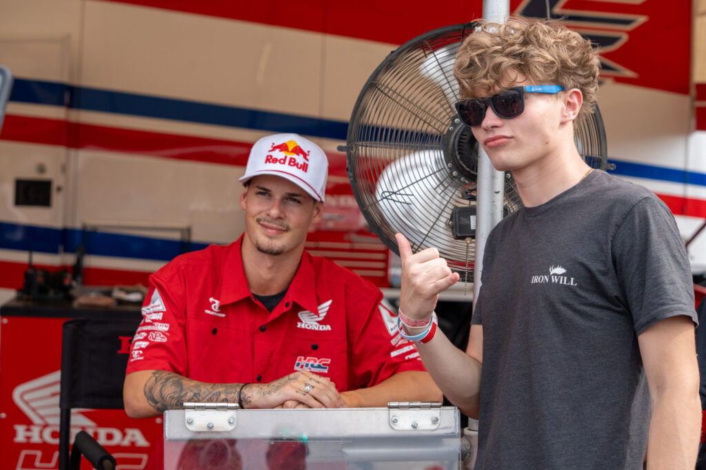 Fan poses with rider in the pit area